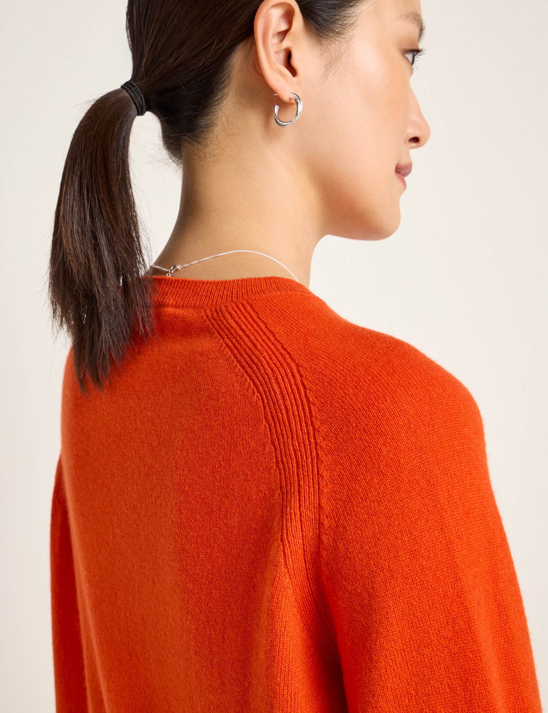 Frau in orangem Pullover von hinten