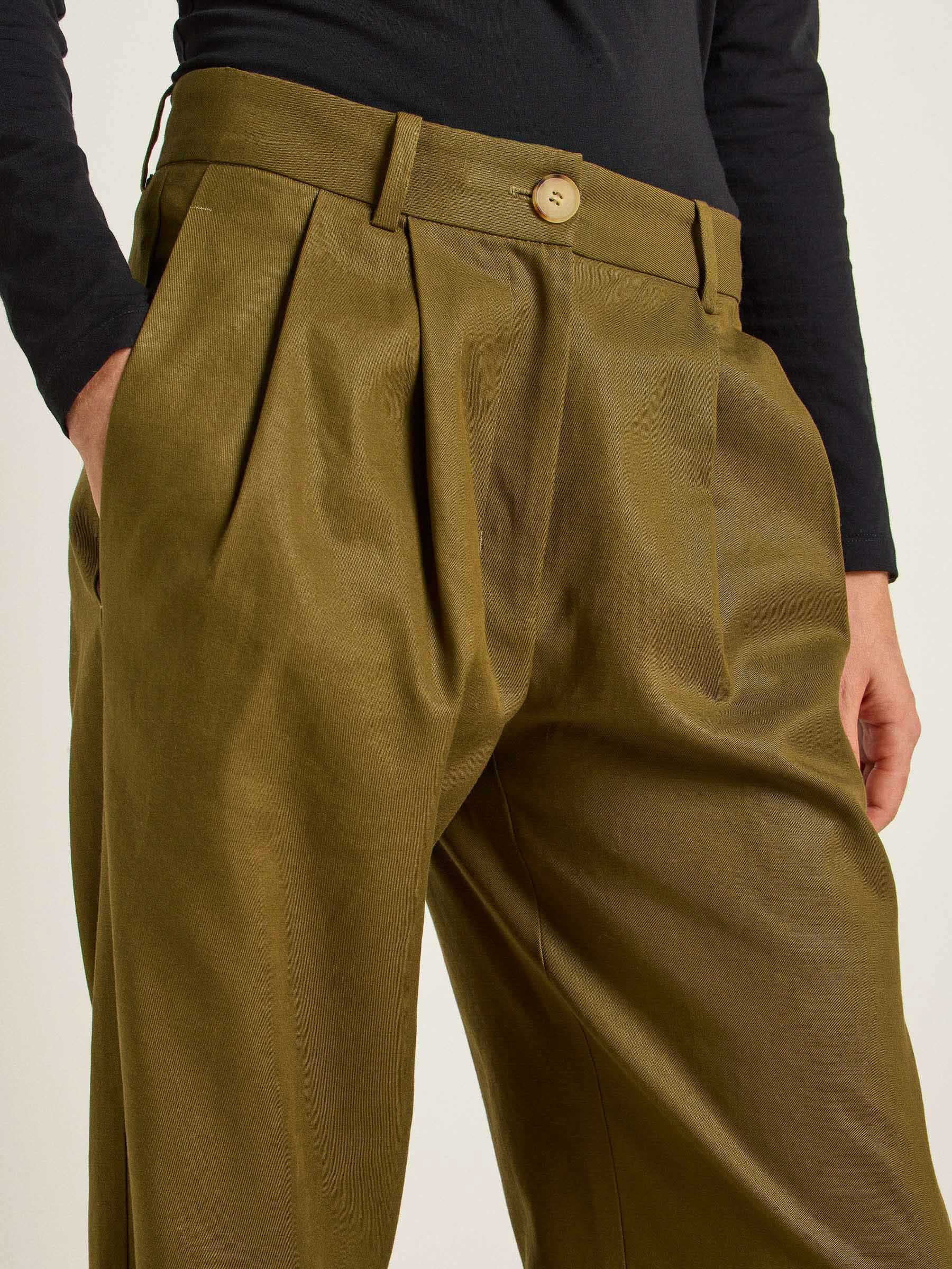 Person trägt olivgrüne Hose mit Knopf