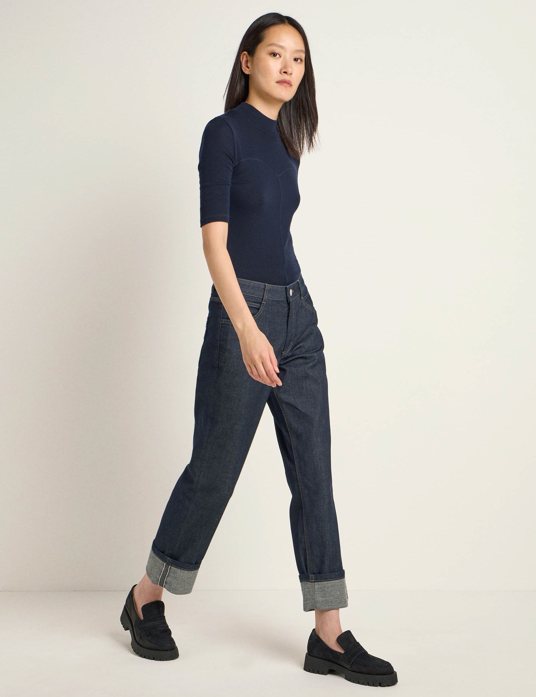 Frau in blauem Shirt und Jeans steht