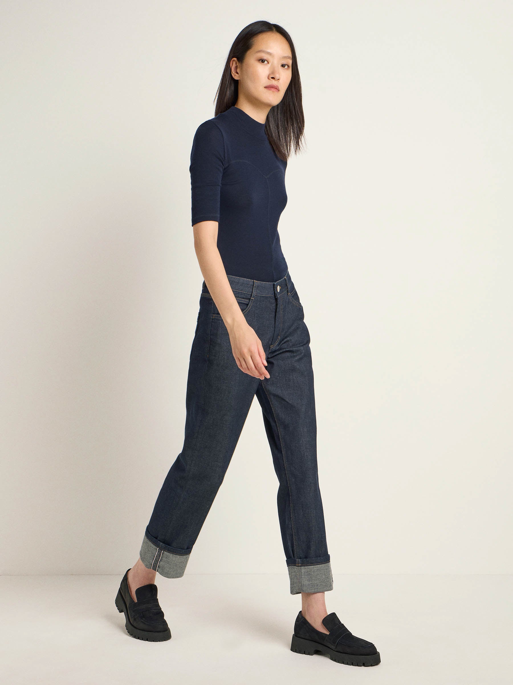 Frau in blauem Shirt und Jeans steht