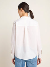 Frau trägt weiße Bluse und Jeans von hinten