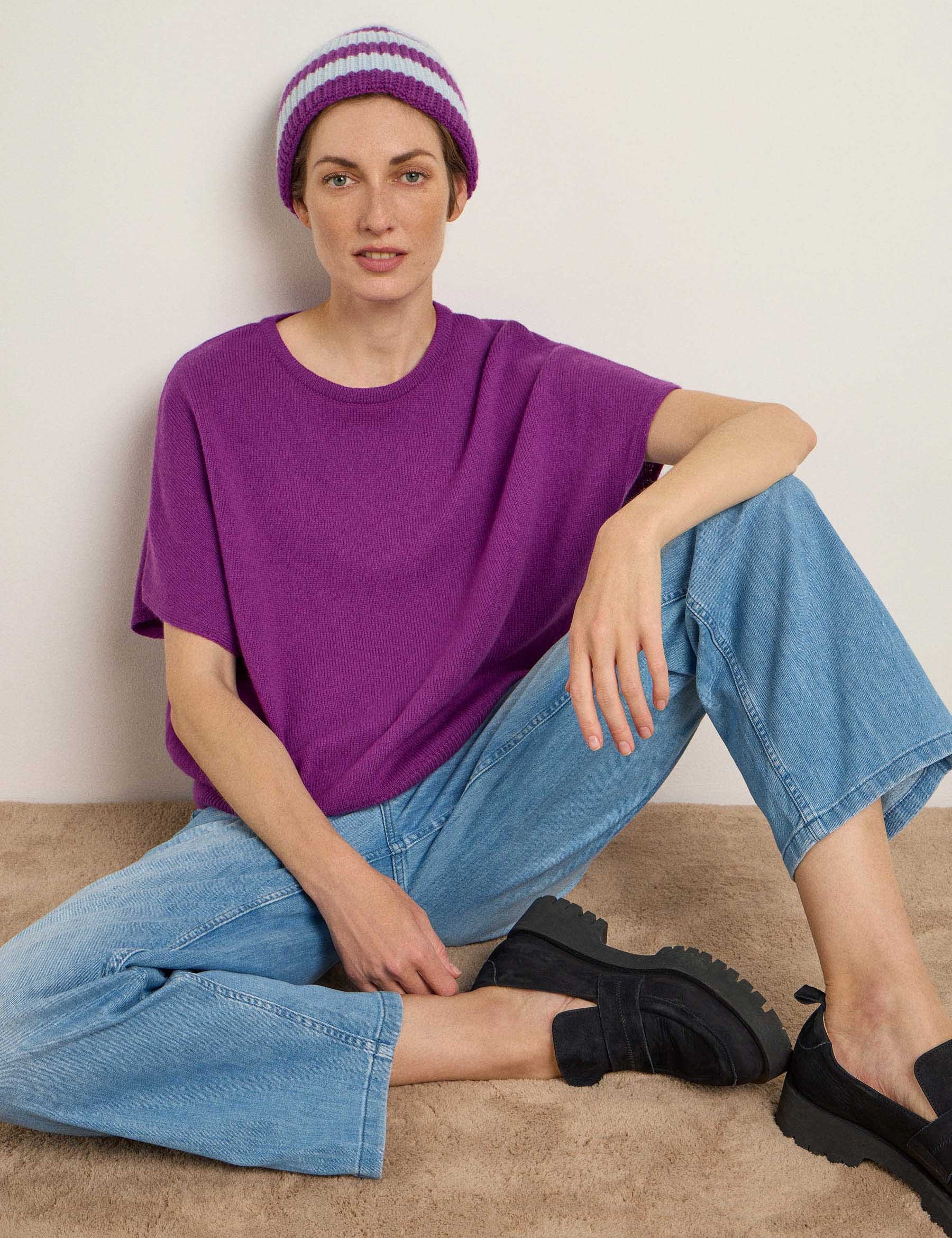 Frau in lila Shirt und blauer Jeans sitzt entspannt