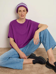 Frau in lila Shirt und blauer Jeans sitzt entspannt