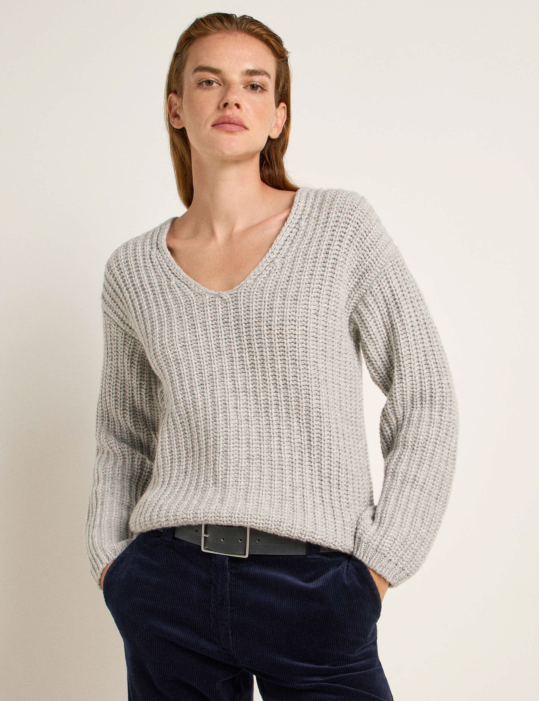 Frau in grauem Pullover und blauen Jeans