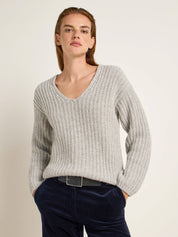 Frau in grauem Pullover und blauen Jeans