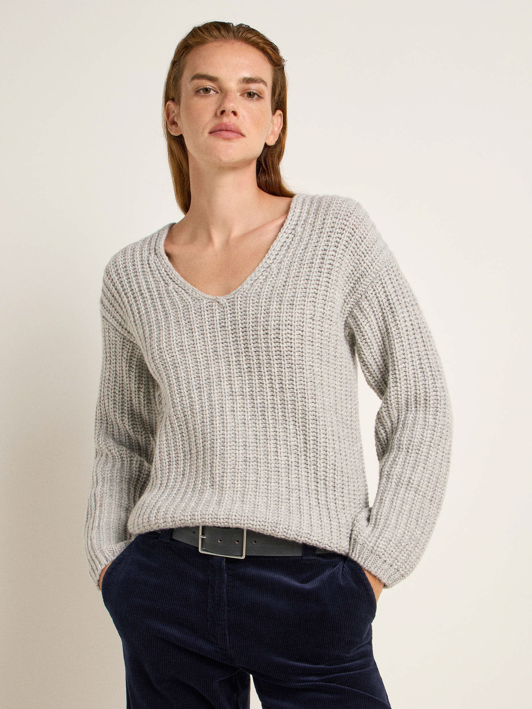 Frau in grauem Pullover und blauen Jeans