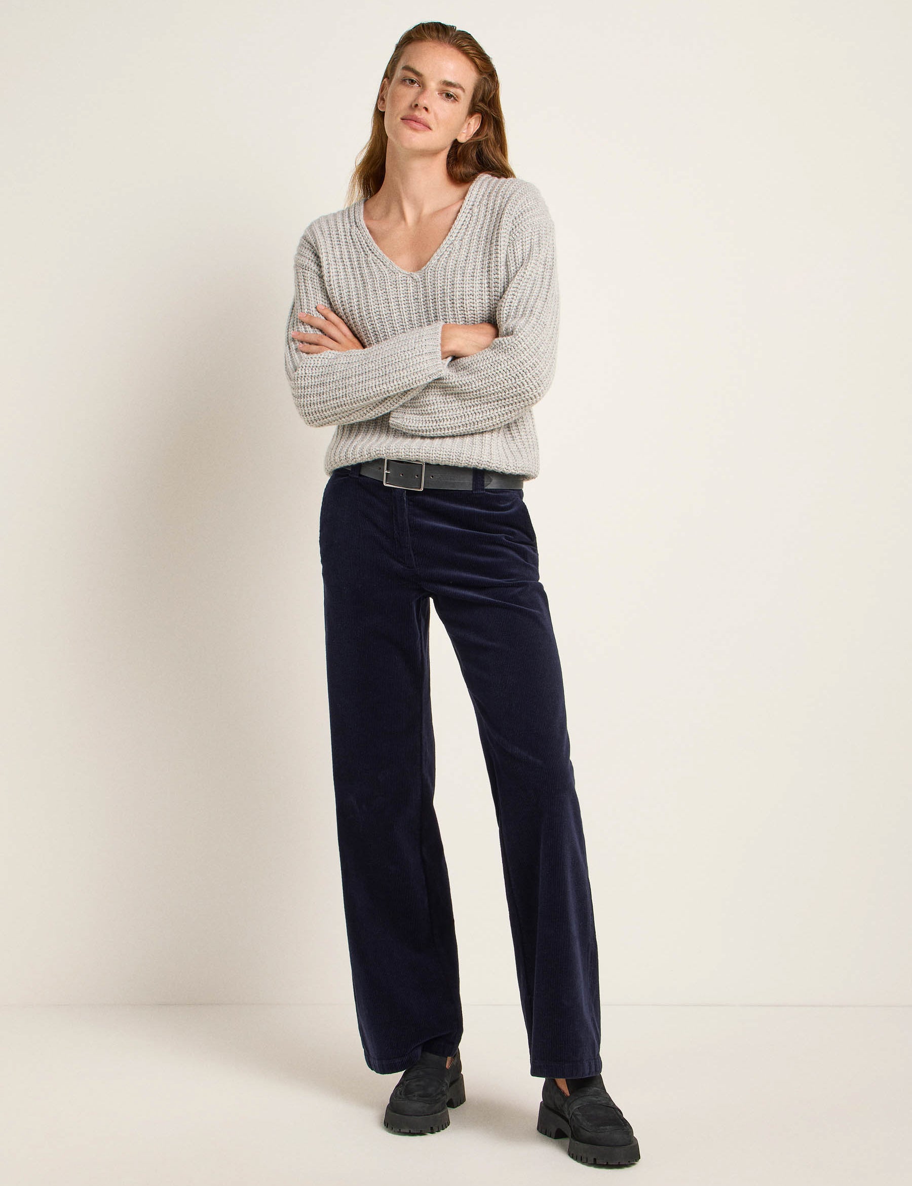 Frau in grauem Pullover und dunkelblauen Hosen