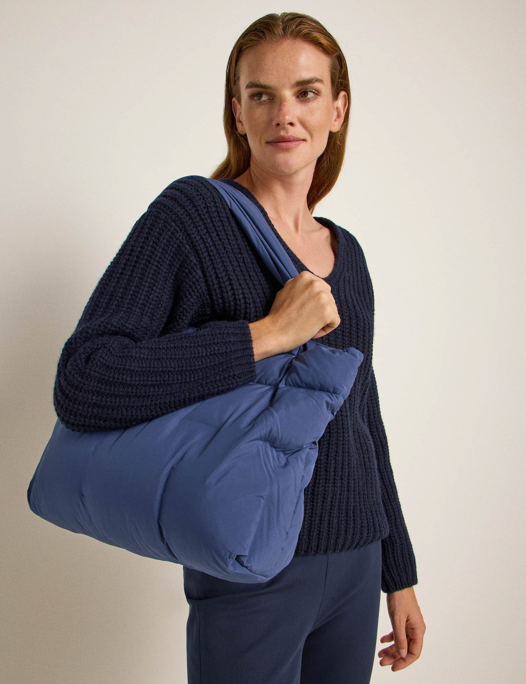 Frau mit blauem Pullover und großer Tasche
