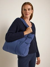 Frau mit blauem Pullover und großer Tasche