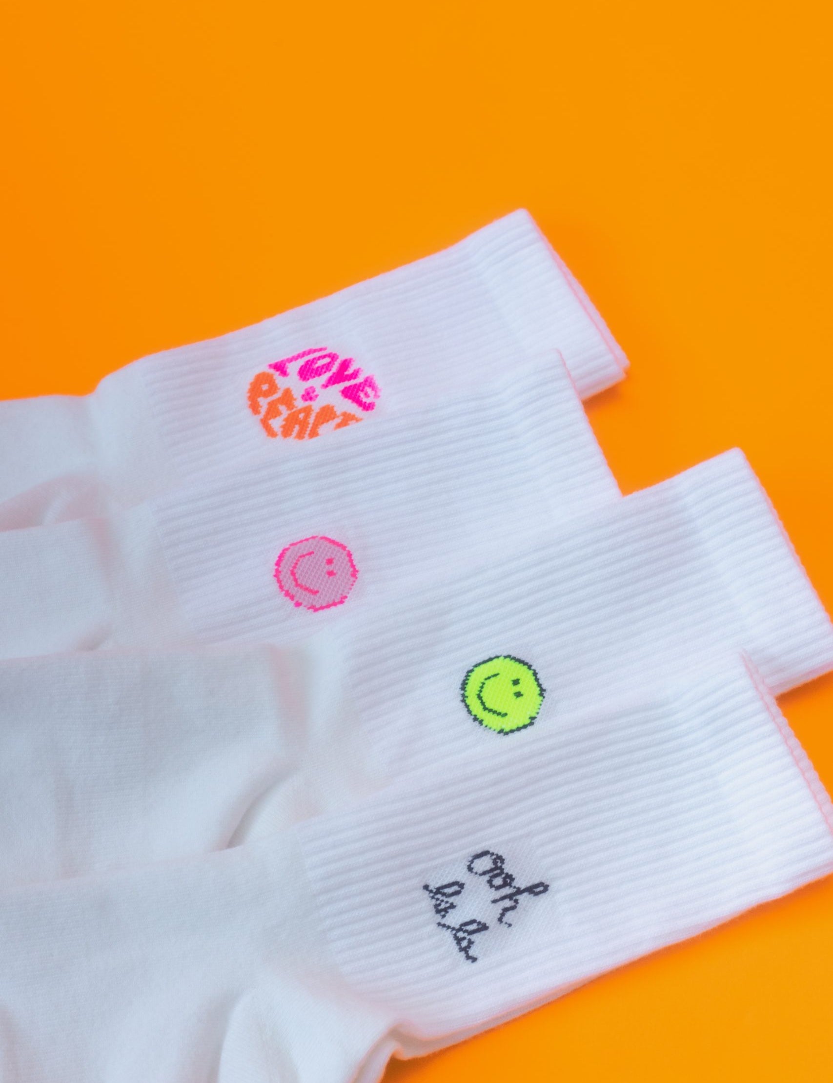 Weiße Socken mit bunten Stickereien auf orange
