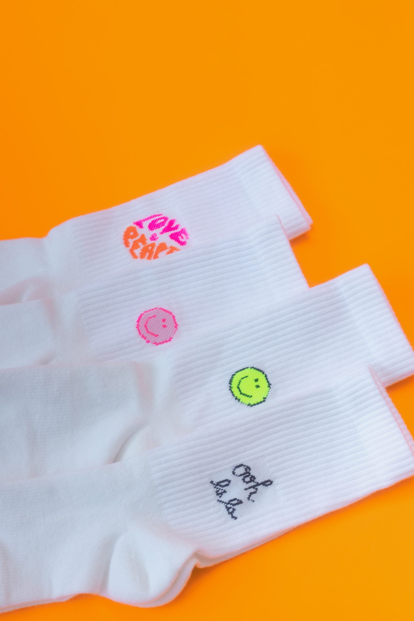 Weiße Socken mit bunten Stickereien auf orange