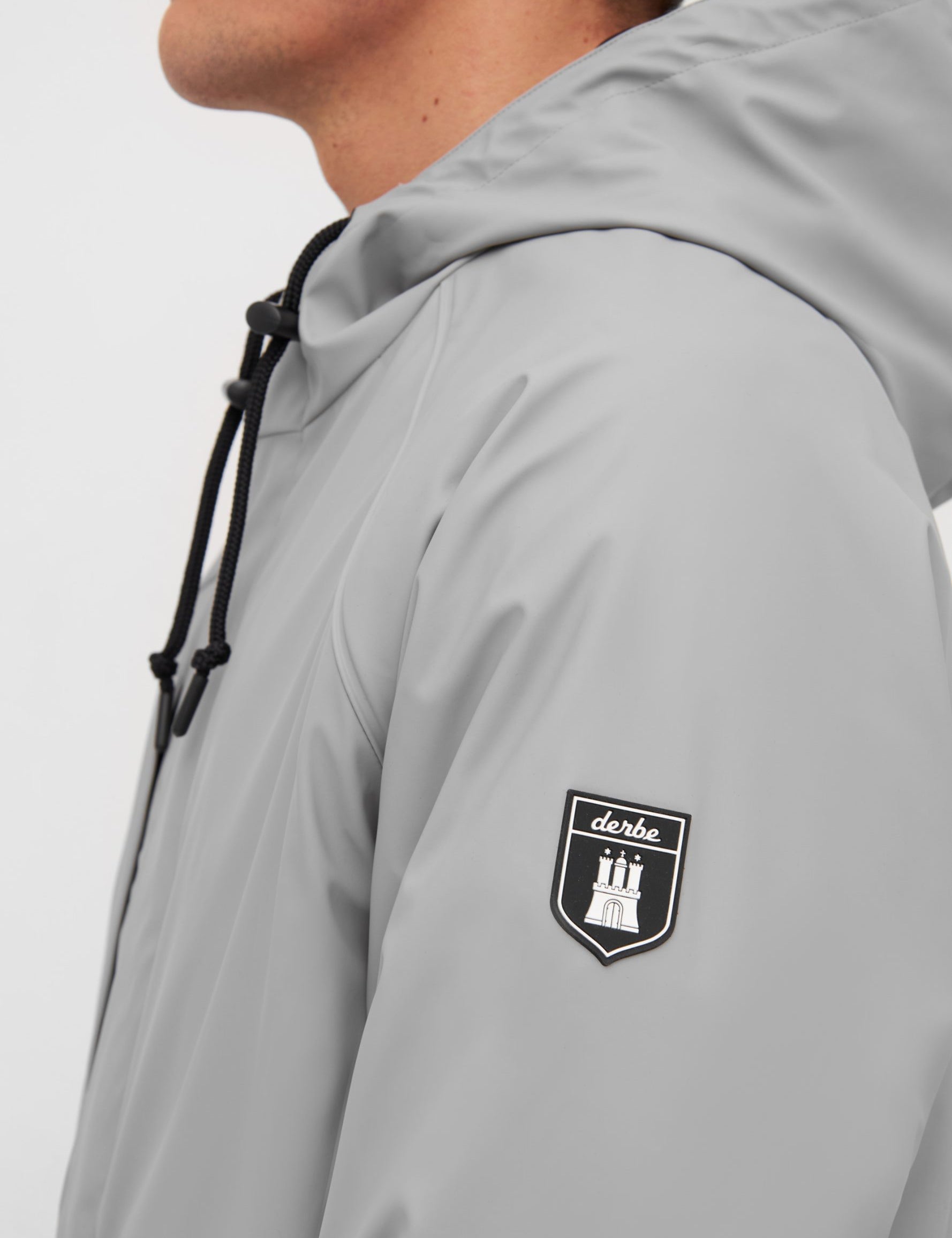 Mann trägt graue Jacke mit Logo