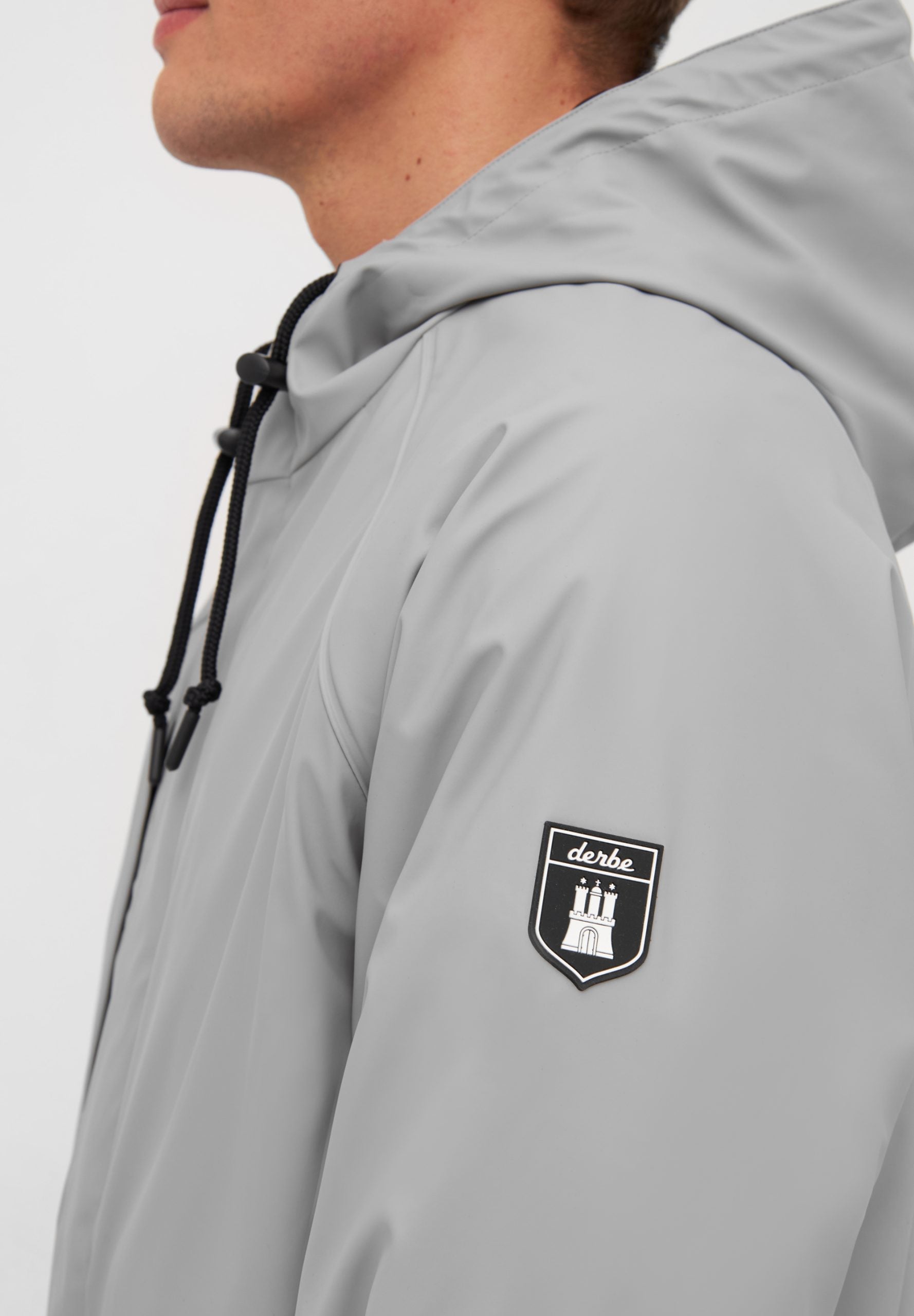 Mann trägt graue Jacke mit Logo