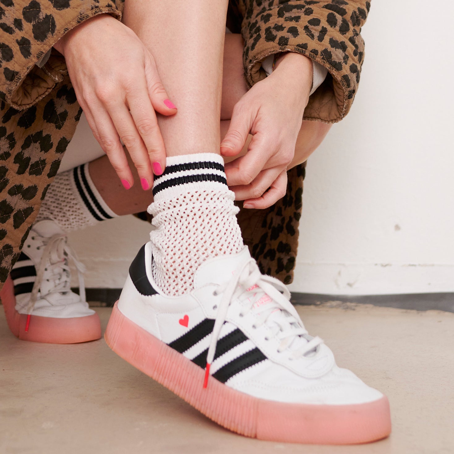 Frau zieht Socke in modischen Sneaker.