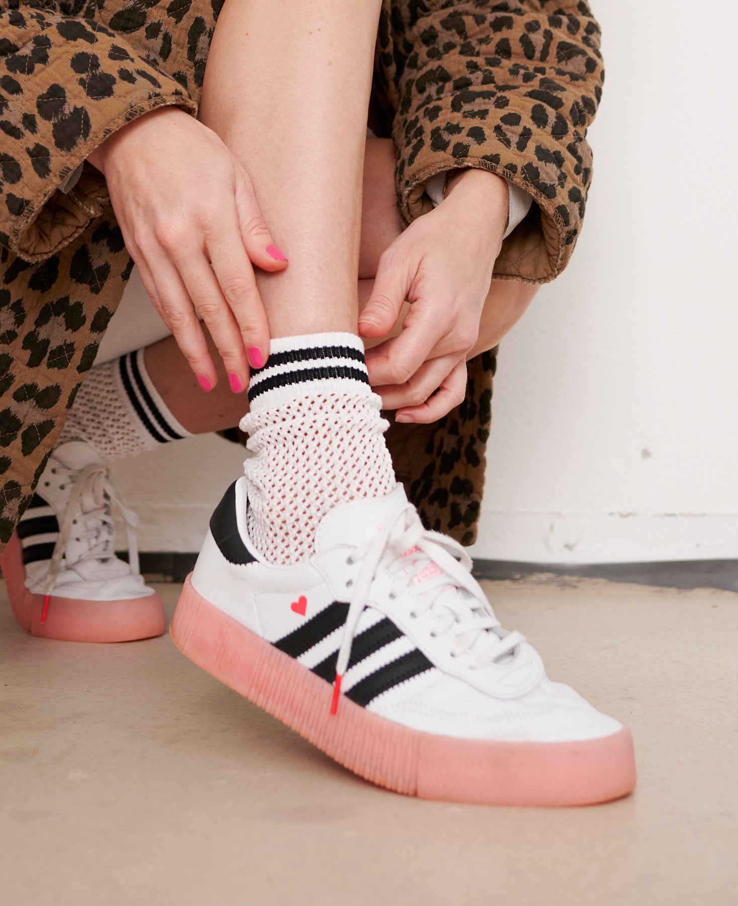 Frau zieht Socke in modischen Sneaker.