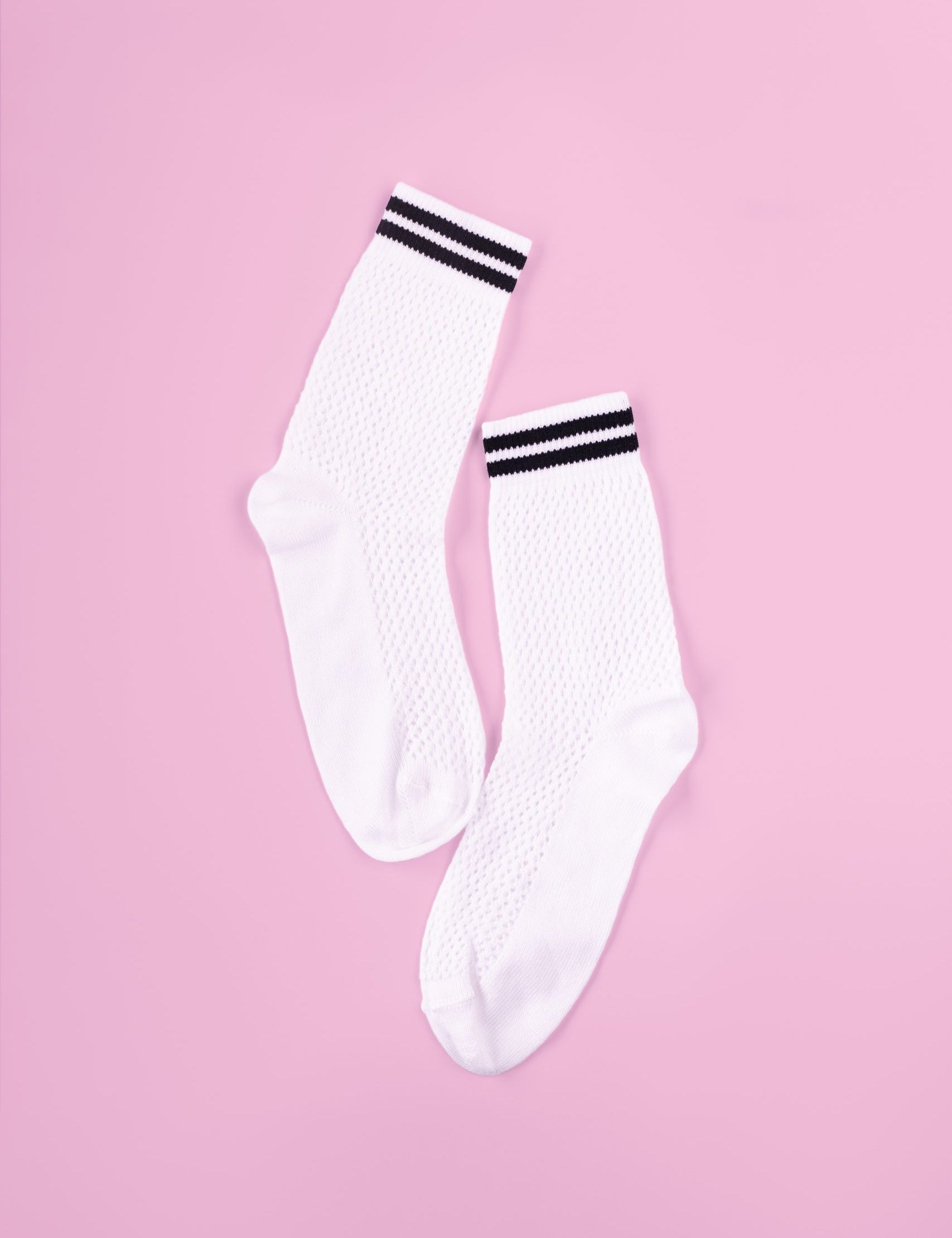 Weiße Socken mit schwarzen Streifen auf rosa Hintergrund.