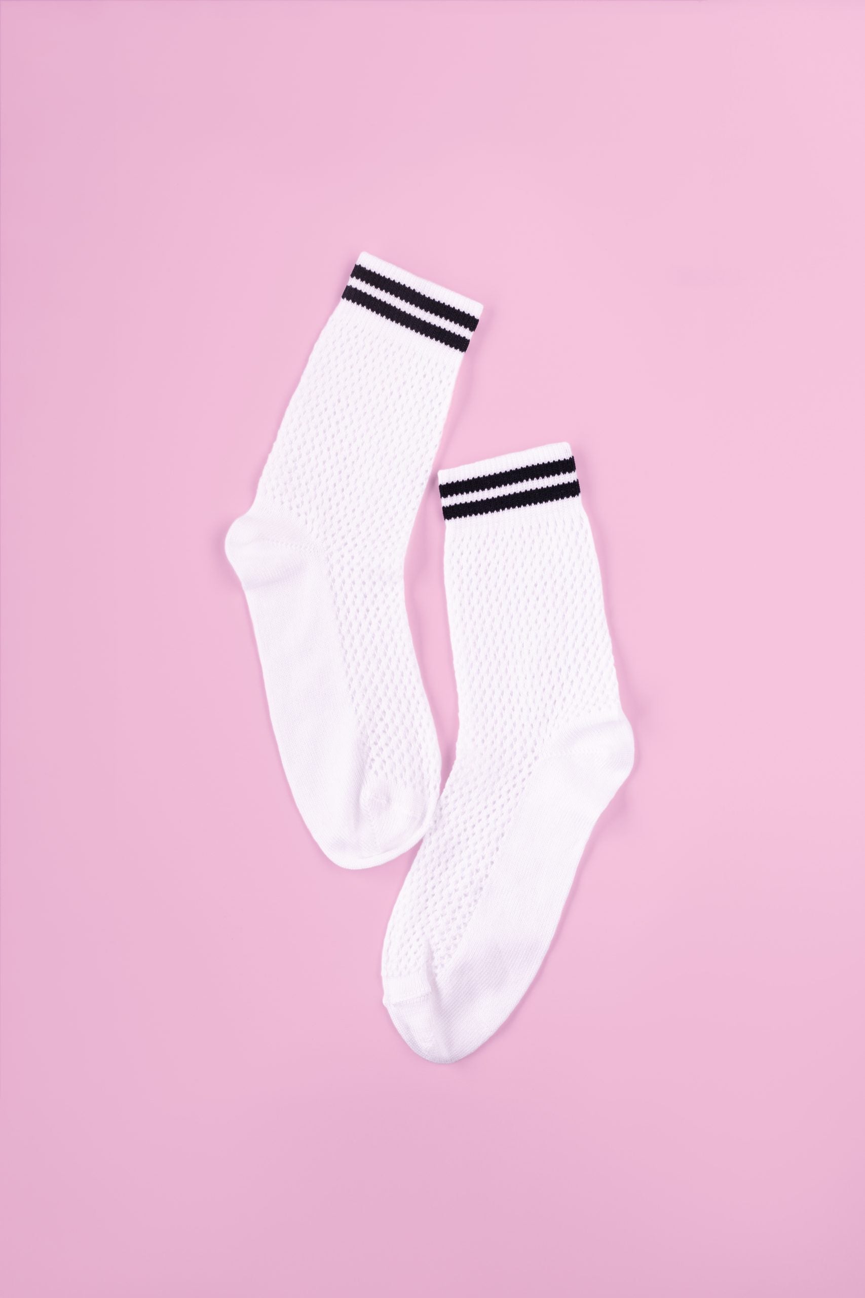 Weiße Socken mit schwarzen Streifen auf rosa Hintergrund.