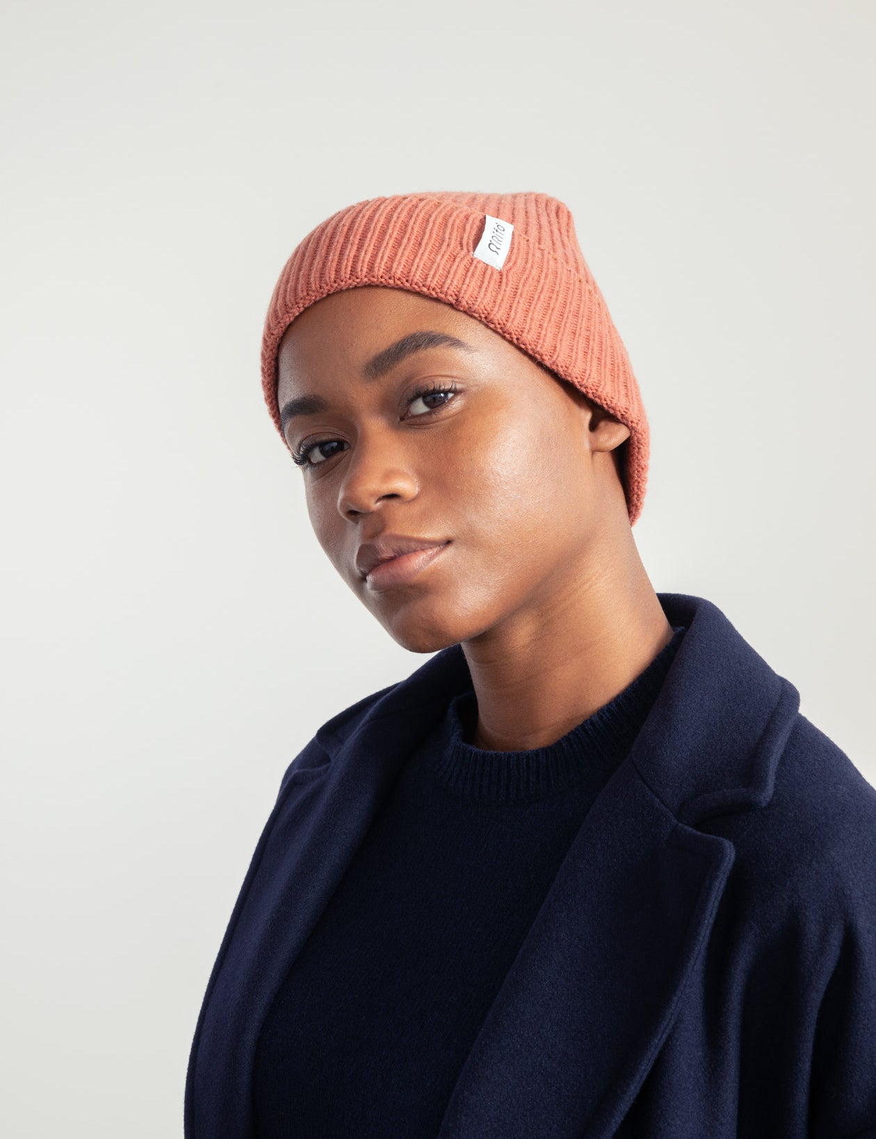 Frau mit Mütze und dunklem Mantel, entspannt.