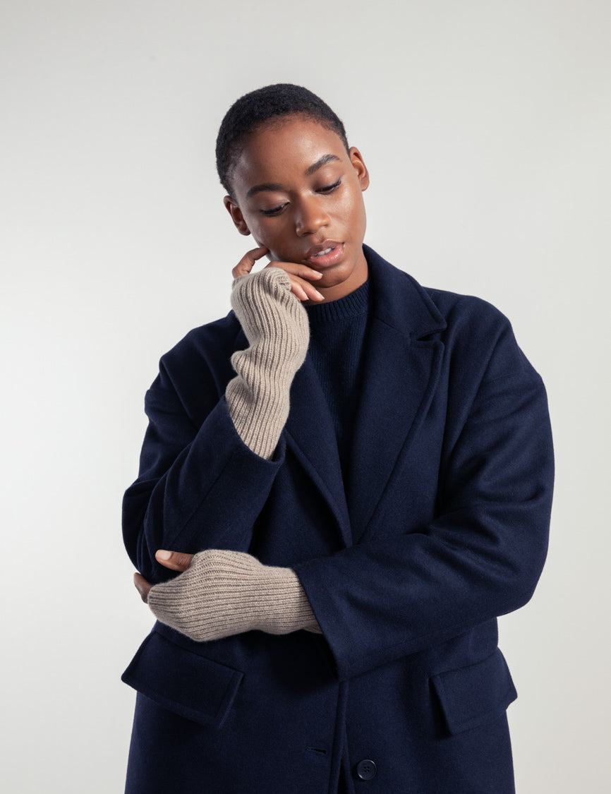 Nachdenkliche Frau in blauem Mantel und Handschuhen