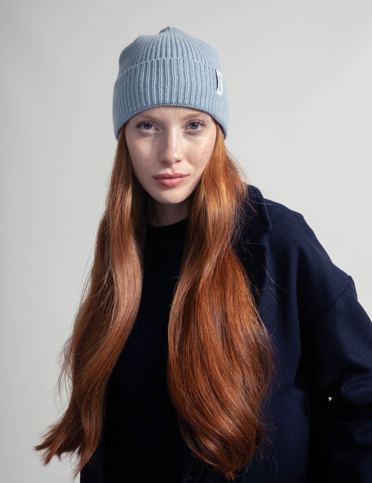 Frau mit roten Haaren trägt Mütze und Mantel
