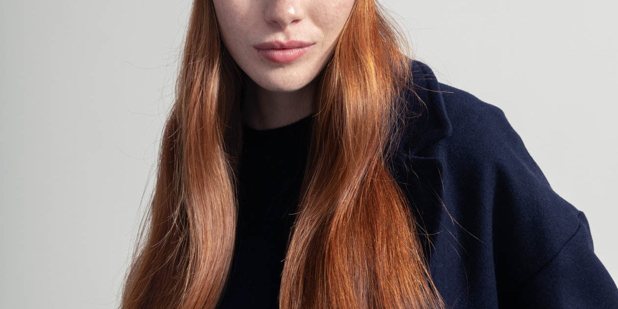 Frau mit roten Haaren trägt Mütze und Mantel