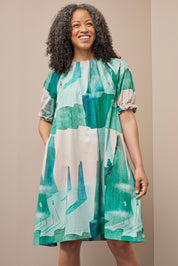 Frau in gemustertem Kleid lacht glücklich.