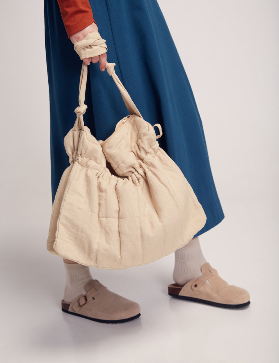 Frau mit blauem Rock hält große Tasche