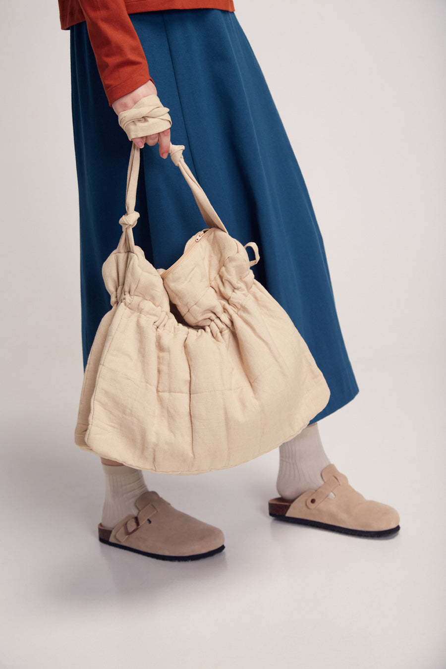 Frau mit blauem Rock hält große Tasche