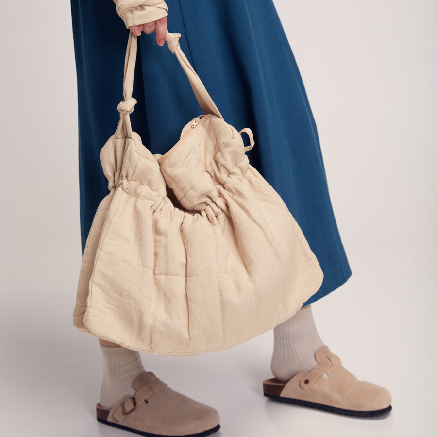 Frau mit blauem Rock hält große Tasche
