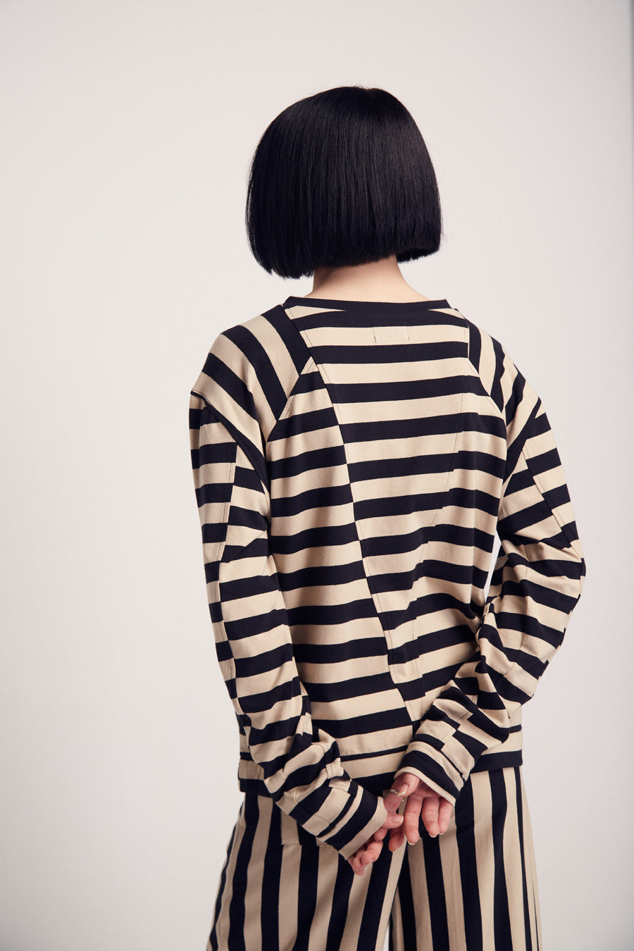 Frau mit schwarzem Bob und gestreiftem Kleid