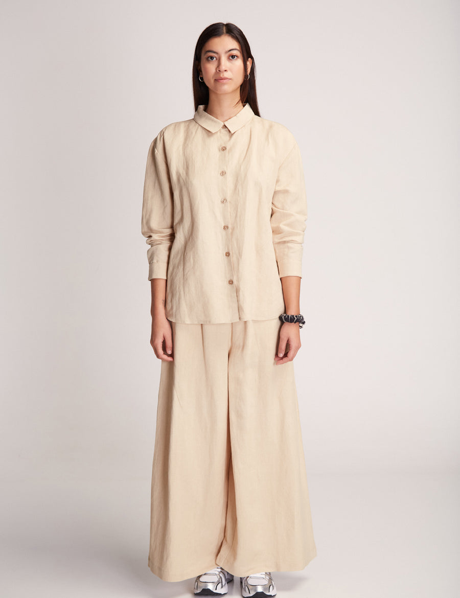 Frau in beiger Bluse und Hose posiert