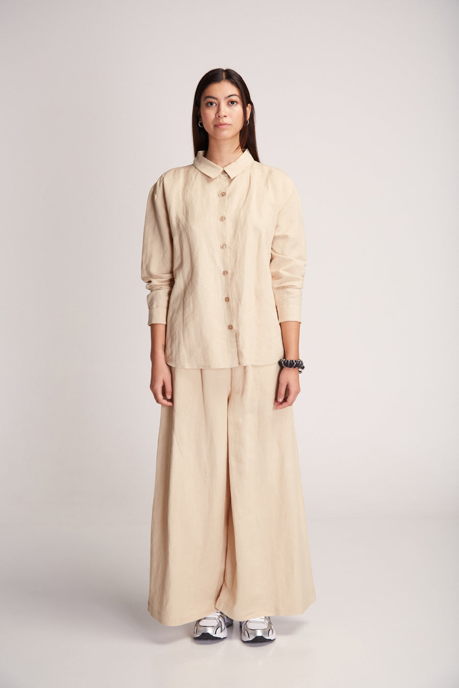 Frau in beiger Bluse und Hose posiert