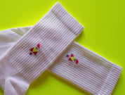 Weiße Socken mit Hühnerstickerei auf grünem Hintergrund