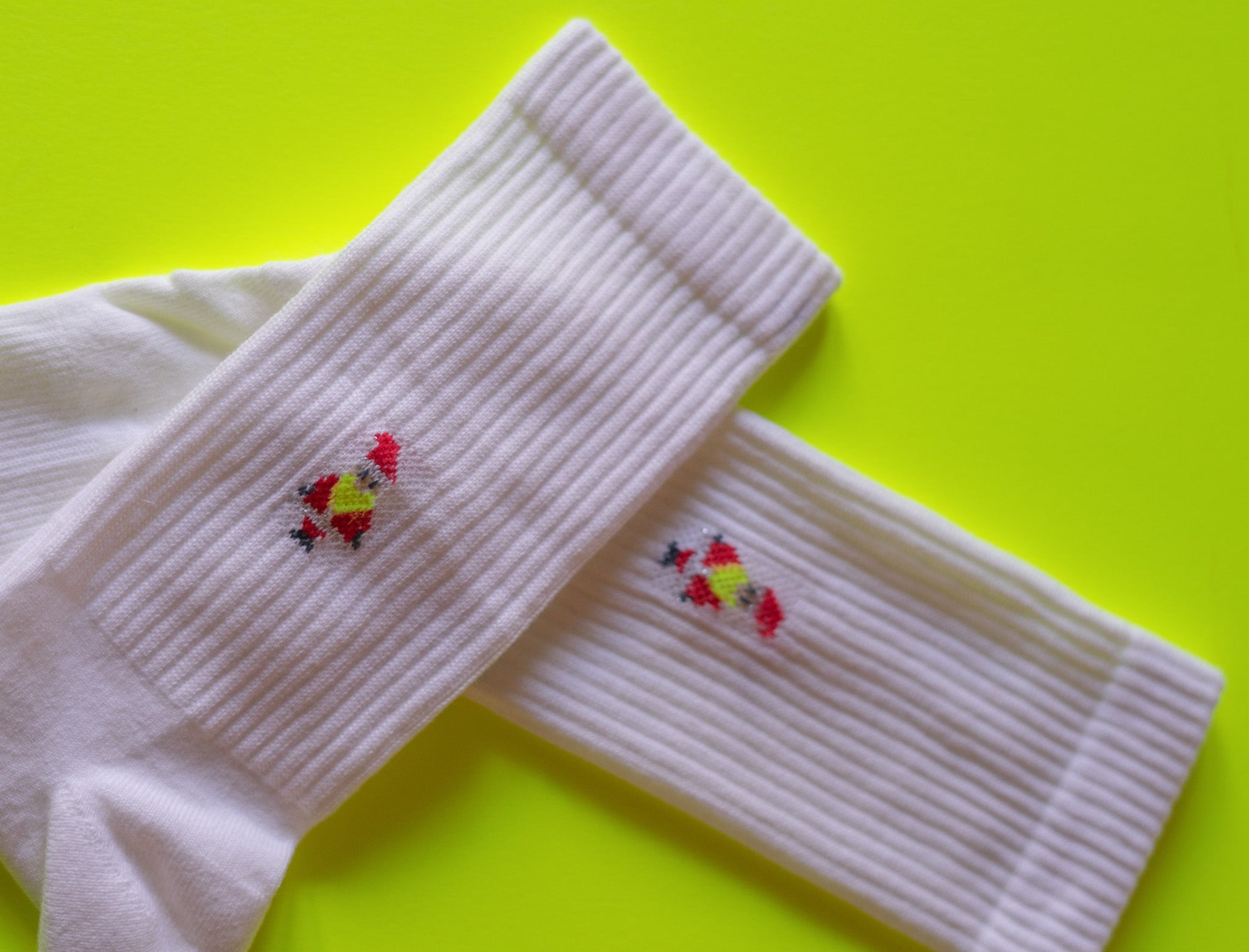 Weiße Socken mit Hühnerstickerei auf grünem Hintergrund