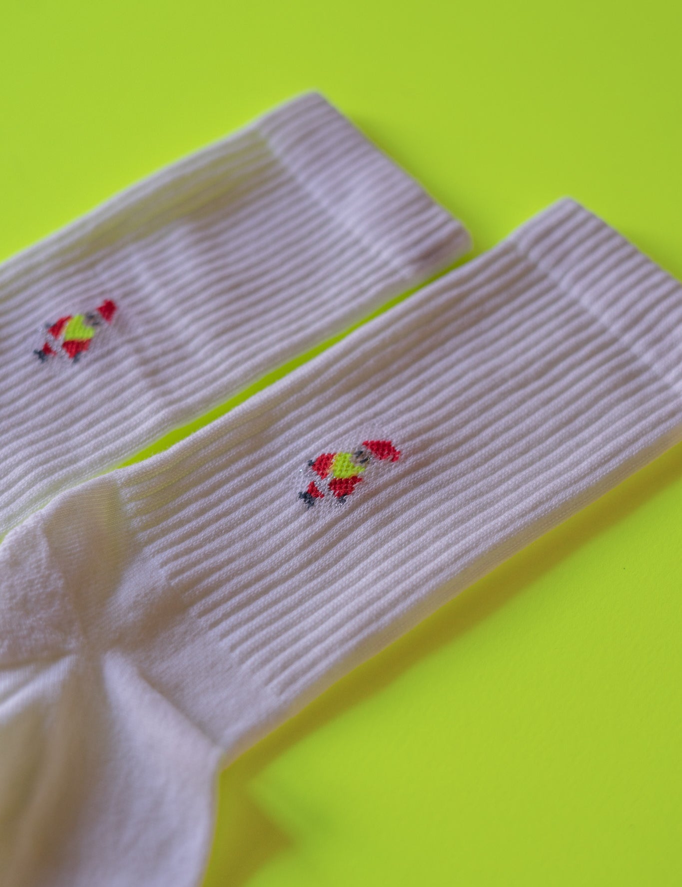 Weiße Socken mit rotem Stickmuster auf gelbem Hintergrund