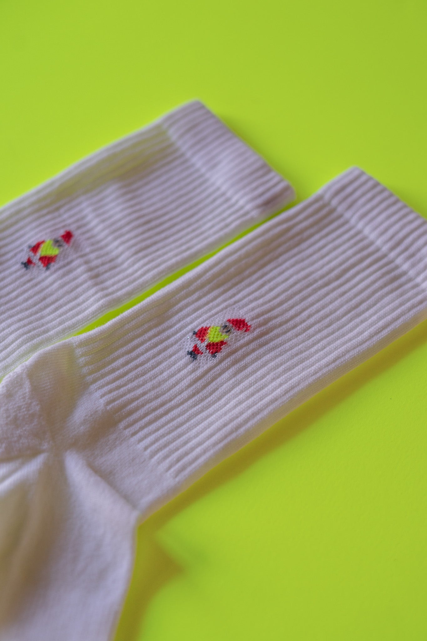 Weiße Socken mit rotem Stickmuster auf gelbem Hintergrund