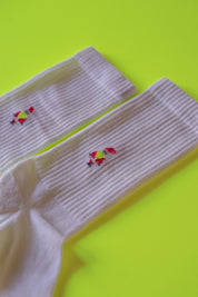 Weiße Socken mit rotem Stickmuster auf gelbem Hintergrund