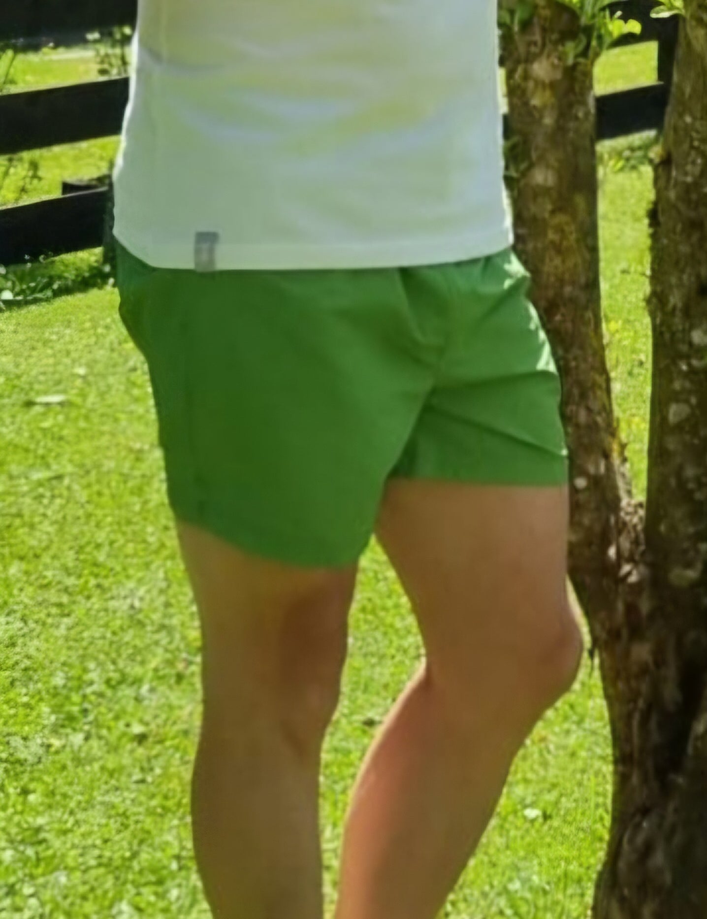 Person steht im Park, trägt grüne Shorts.