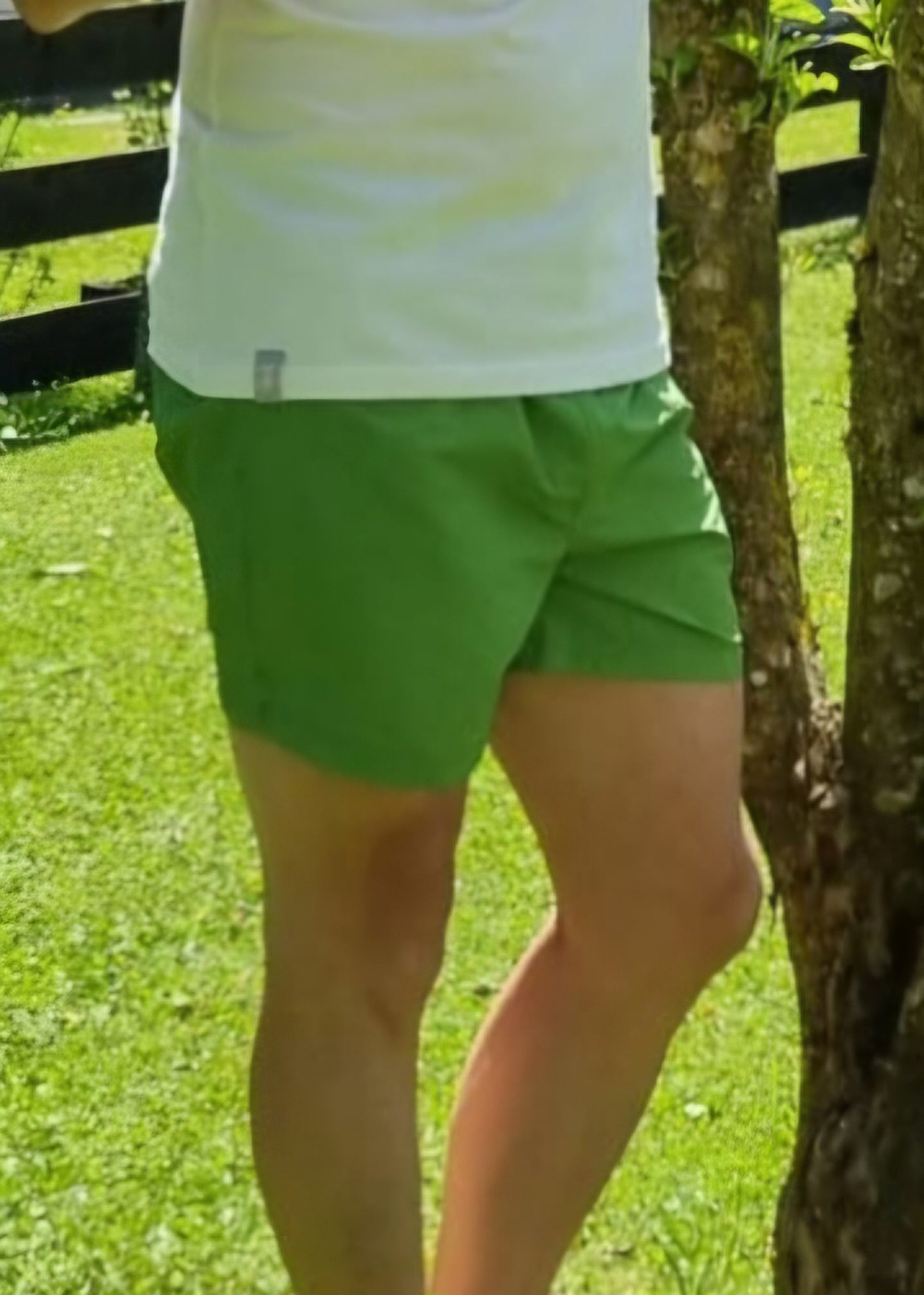 Person steht im Park, trägt grüne Shorts.