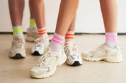 Drei Paar Beine in modischen Sneakern und Socken.