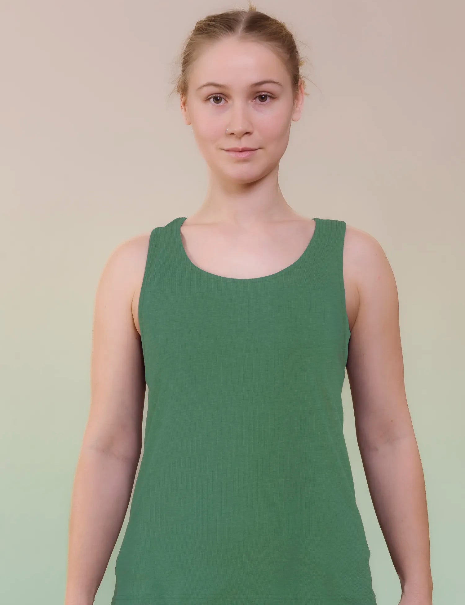Junge Frau in grünem Tanktop steht frontal.