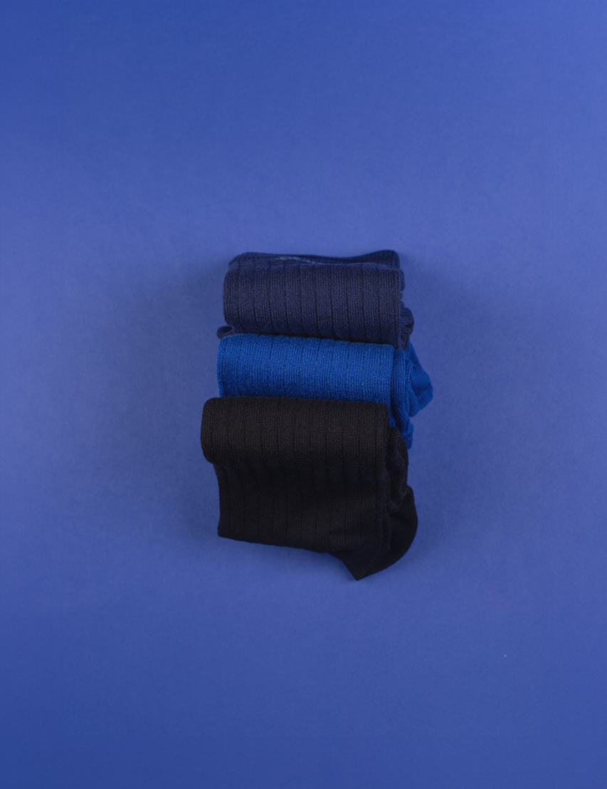 Gestapelte blaue und schwarze Socken auf blauem Hintergrund