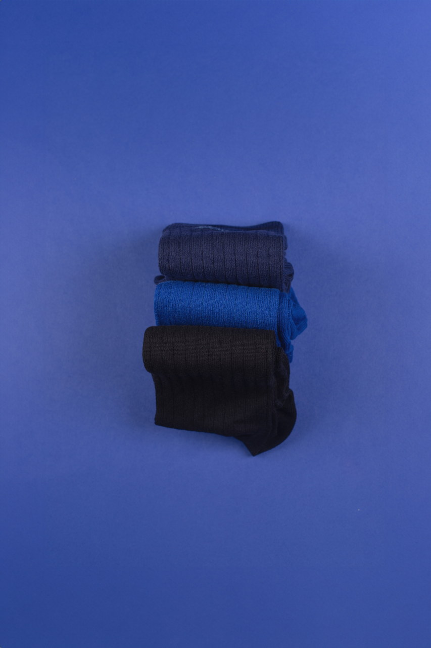 Gestapelte blaue und schwarze Socken auf blauem Hintergrund