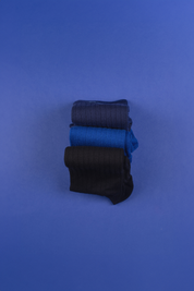 Gestapelte blaue und schwarze Socken auf blauem Hintergrund