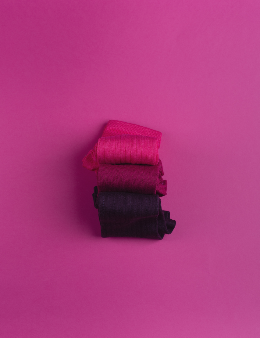 Drei gerollte Stoffe auf pinkem Hintergrund