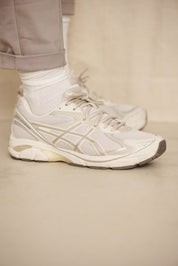 Person trägt weiße Sneaker und beige Hose