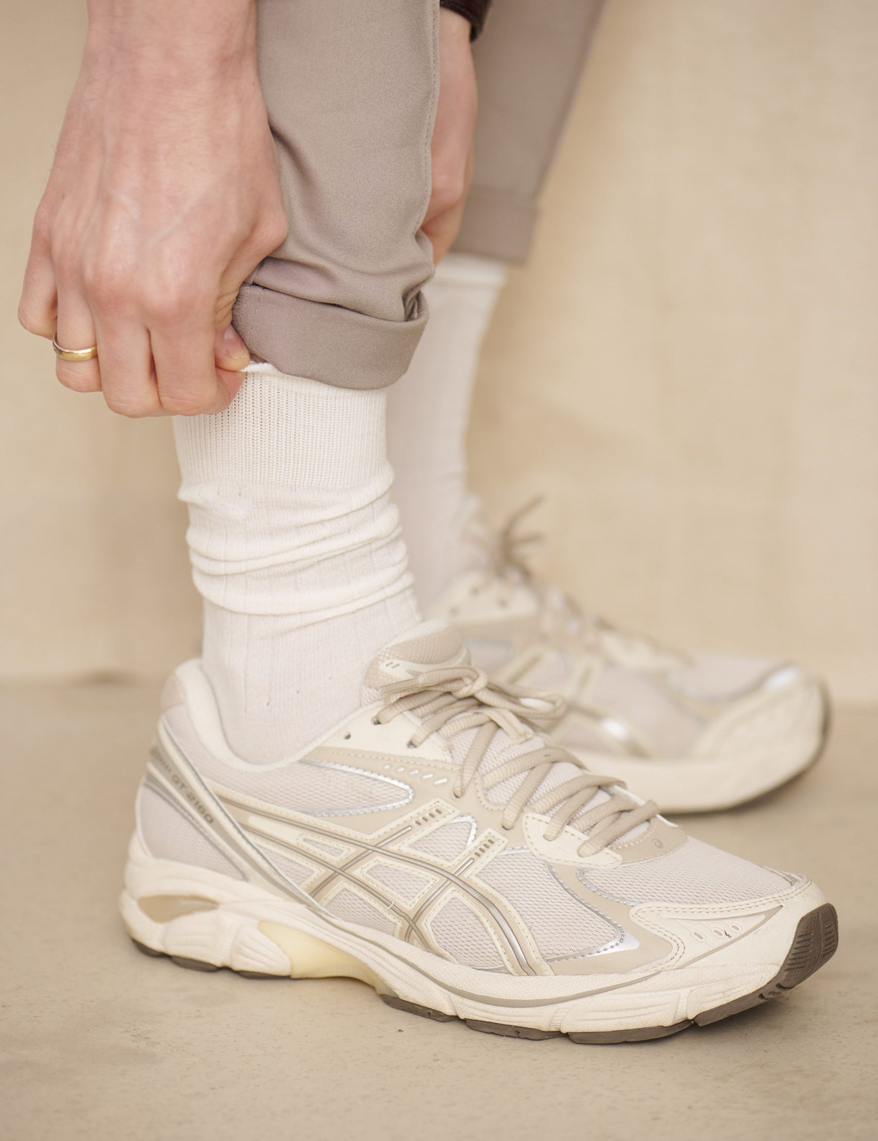 Person trägt weiße Sneaker und beigefarbene Hose