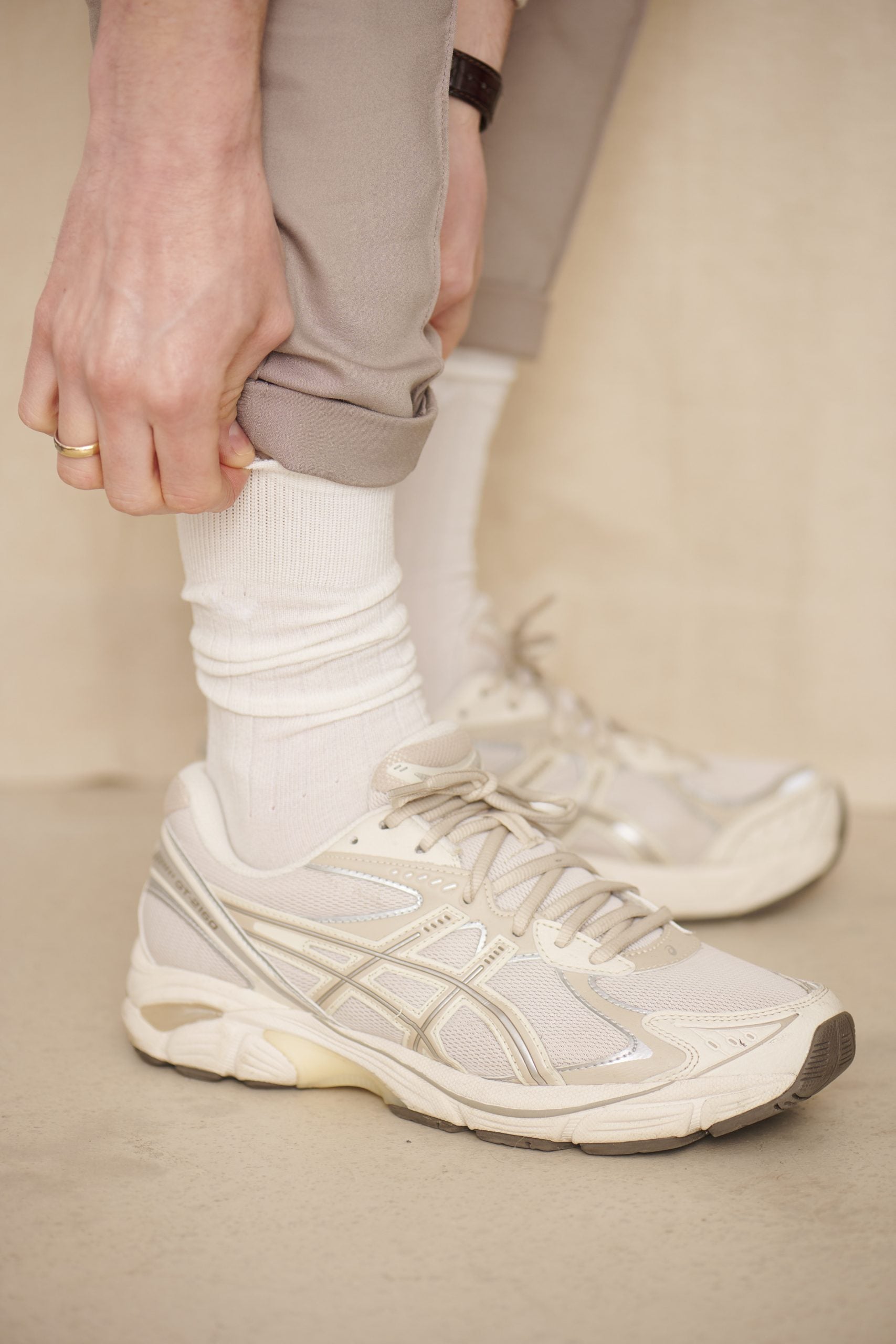 Person trägt weiße Sneaker und beigefarbene Hose