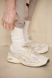 Person trägt weiße Sneaker und beigefarbene Hose