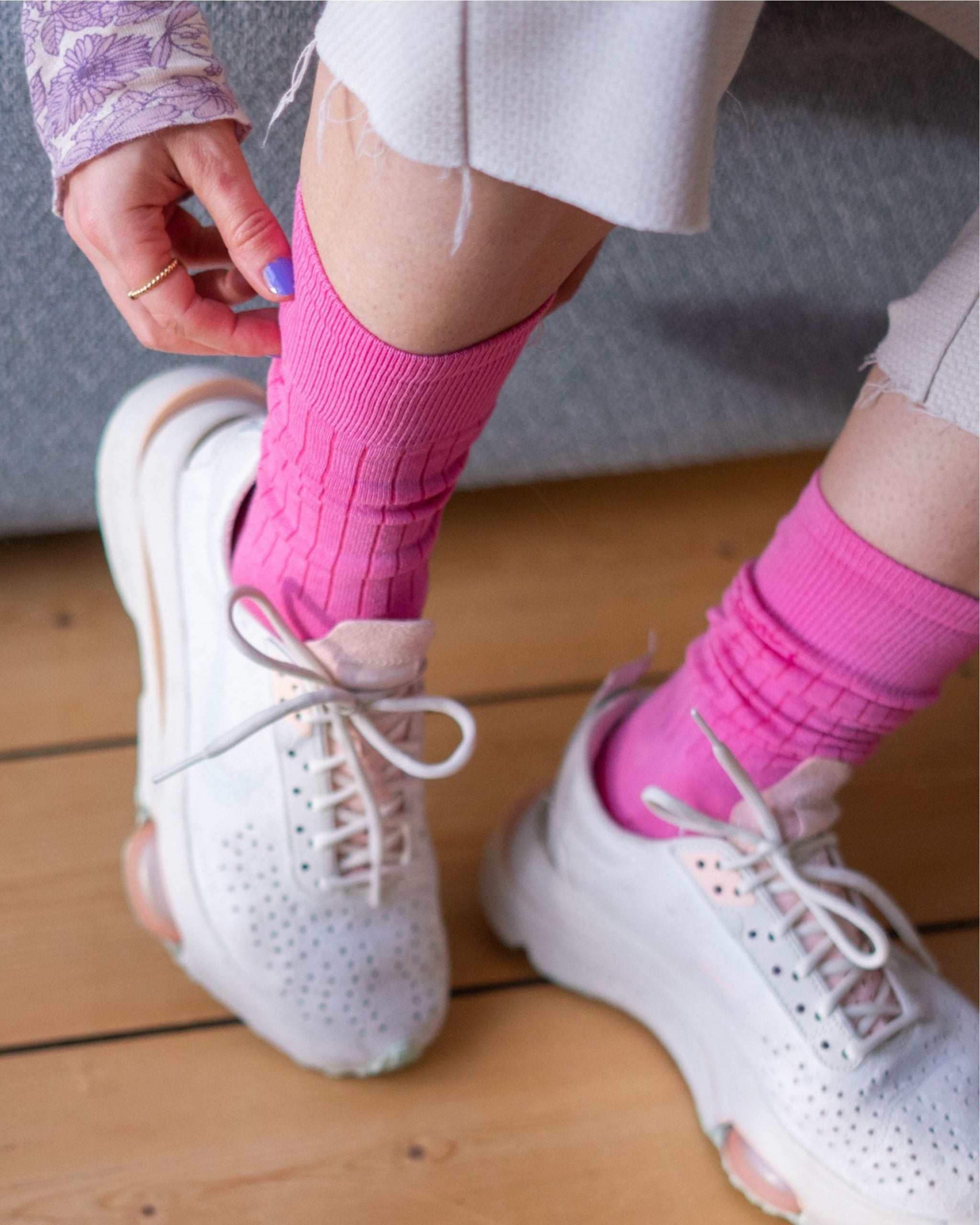 Frau in rosa Socken zieht Sneaker an.